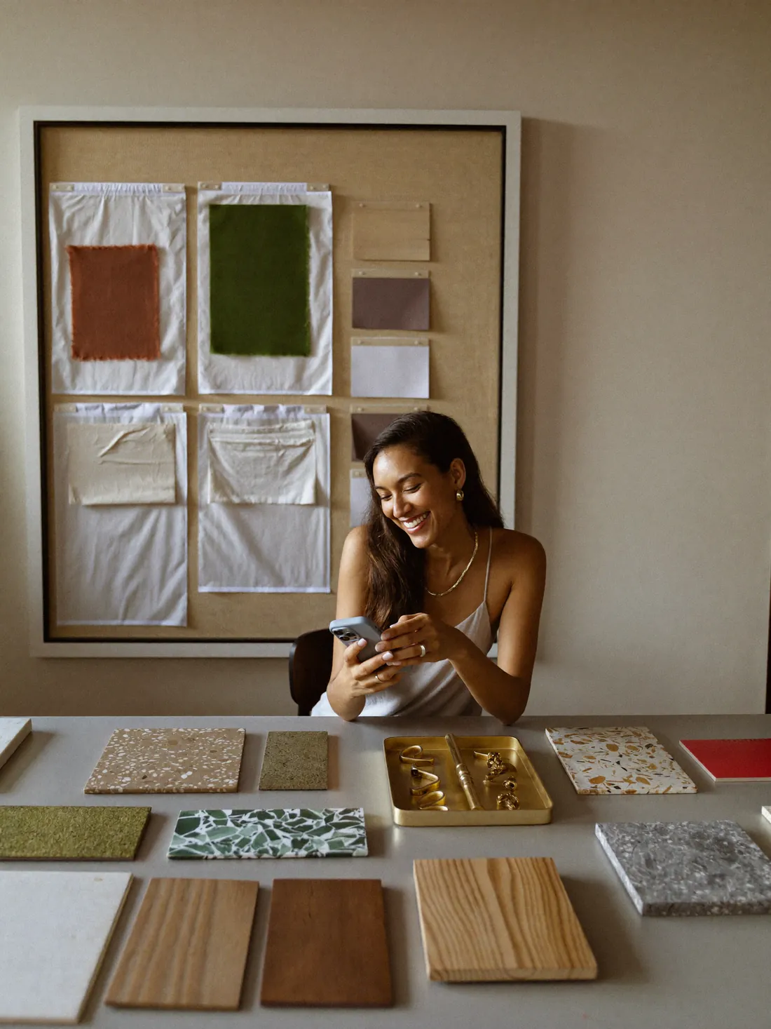 An interior designer smiling at her phone among material samples
