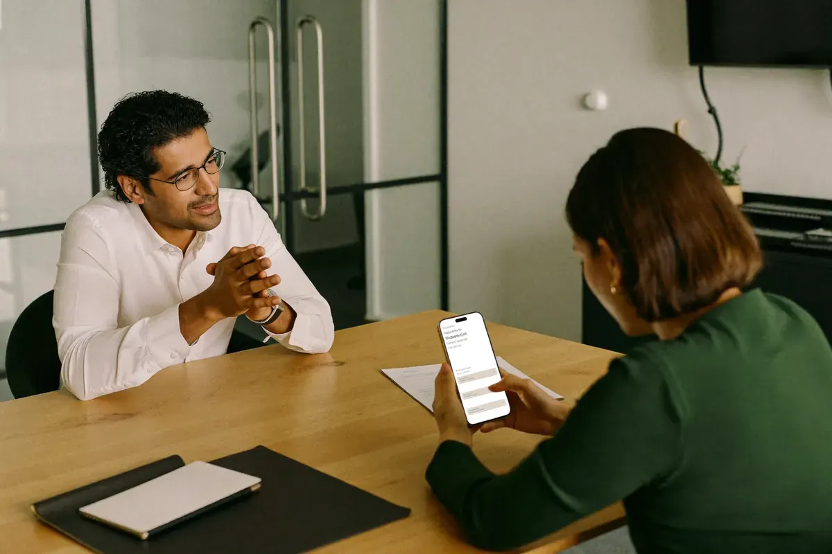 A founder showing a link on her phone across a meeting table